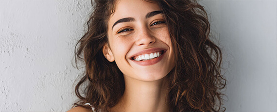 woman with big smile leaning agains outdoor wall