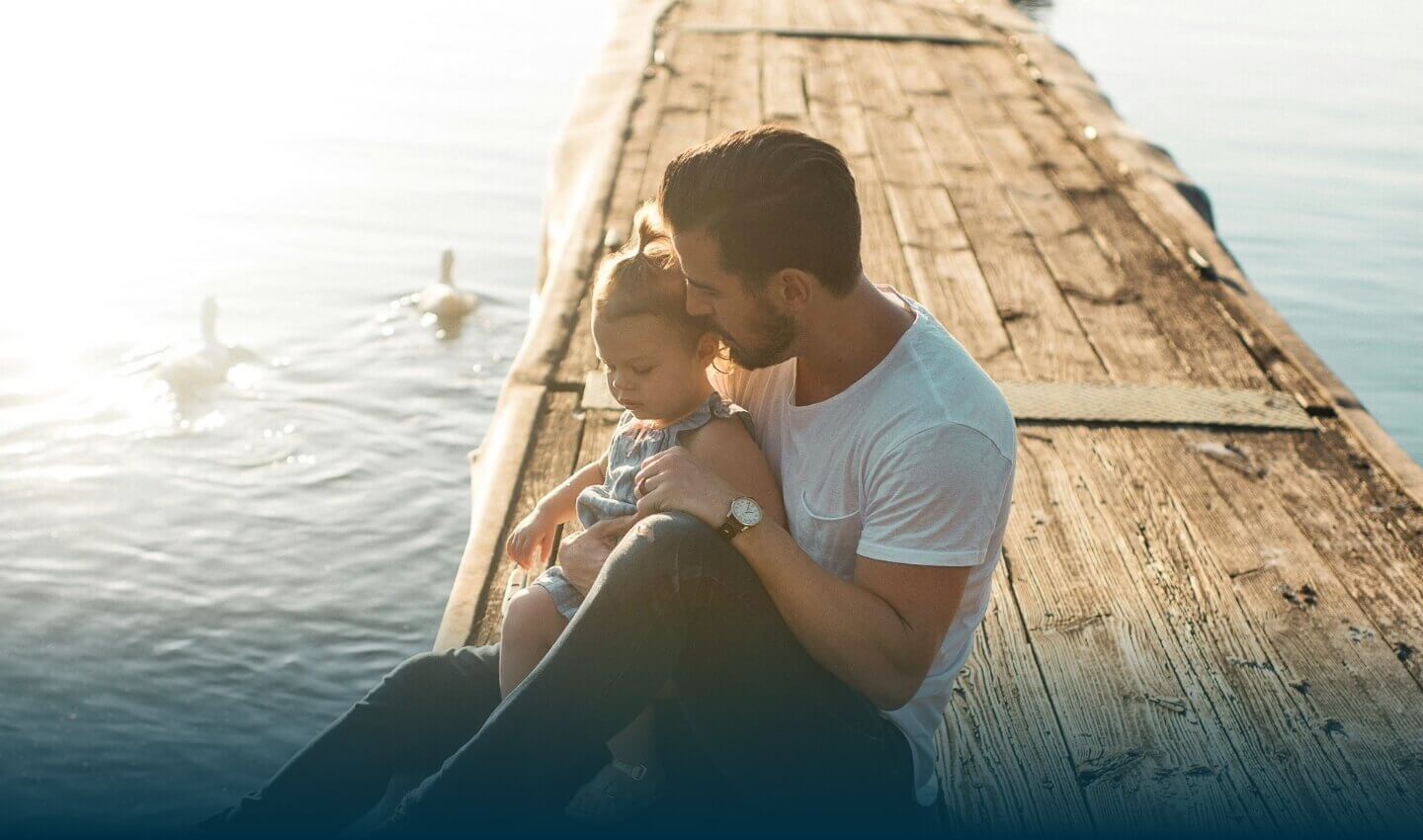 Father and daughter sitting by a lake