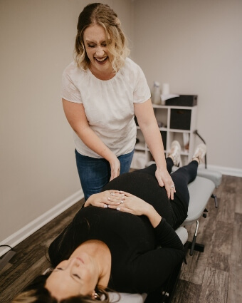 Dr. Leslie smiling while adjusting a pregnant patient