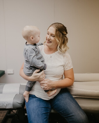 Dr. Leslie smiling while holding a baby