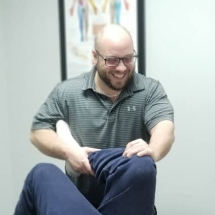 Dr Jason smiling and adjusting patients leg