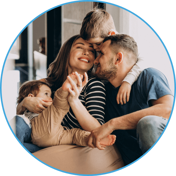 happy family of four hugging on couch