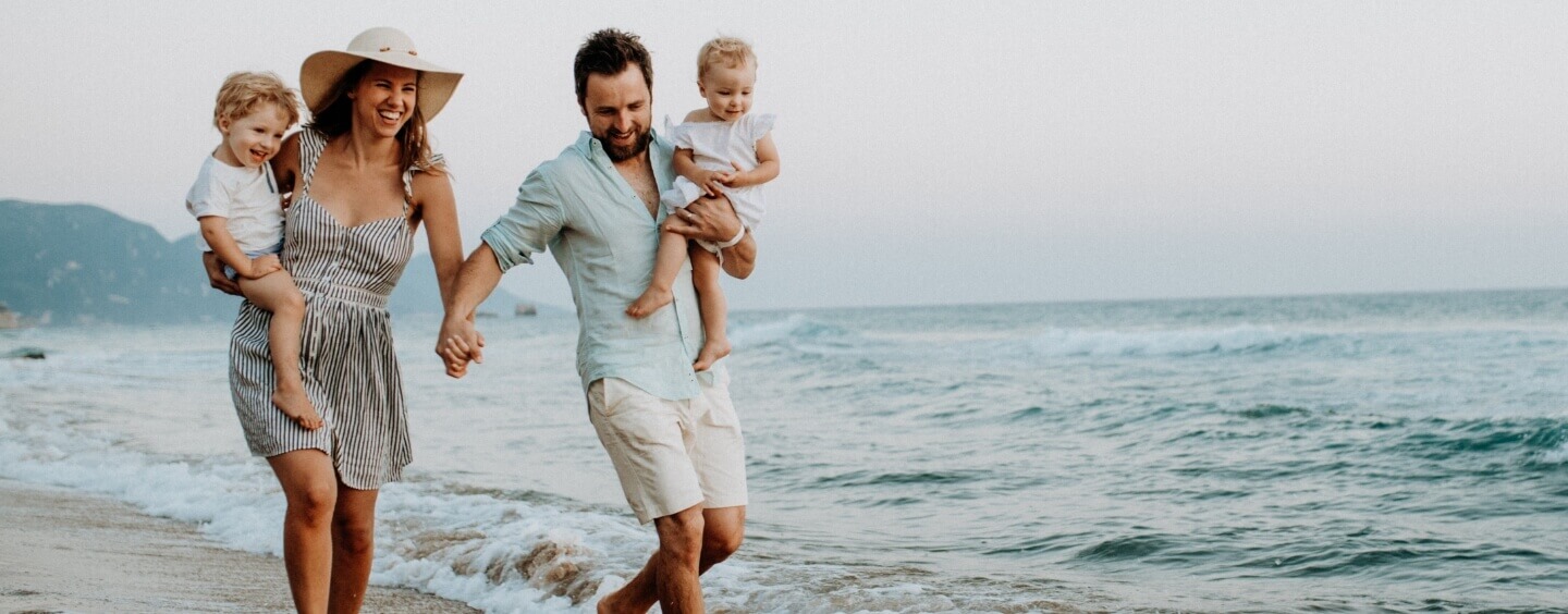 couple holding hands walking on beach with kids