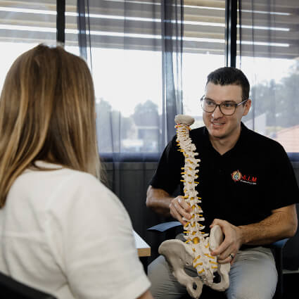 Dr Luke of A.I.M Muscles and Joints explaining treatment to female patient