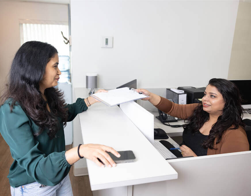 Receptionist handing paperwork to patient