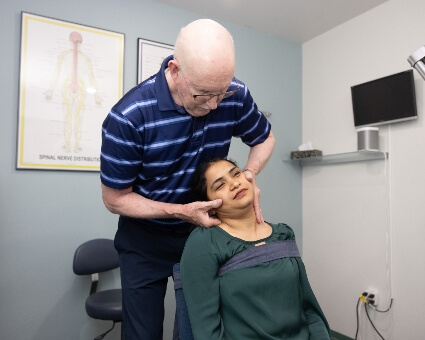 Dr. Prii adjusts female patient's neck