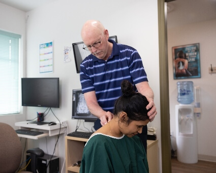 Dr. Prii adjusting female patient's neck