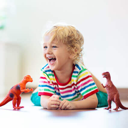 child playing on floor with dinosauers