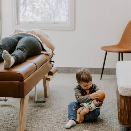child sitting next to parent who is laying on adjusting table