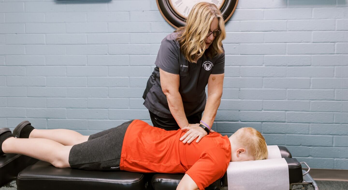 Grain Valley Chiropractor Dr Catherine Dowd adjusting boy's back on adjusting table