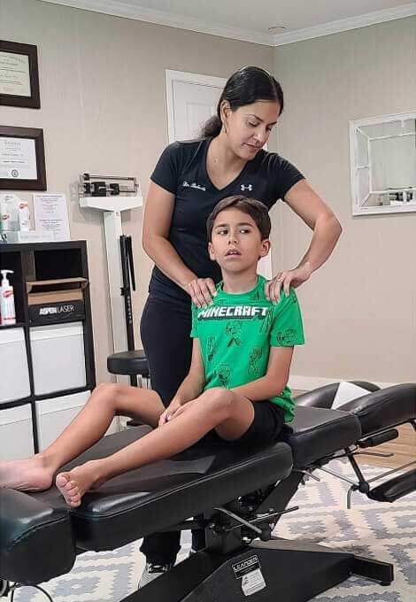 Kid in green shirt being adjusted at Essentials for Wellness Family Chiropractic