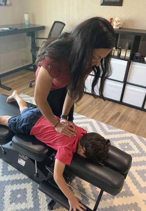 Kid in red shirt being adjusted by Roanoke chiropractor