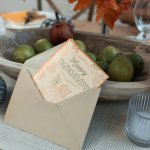 Thanksgiving card displayed with autumn fruits and decor creating a festive table setting.