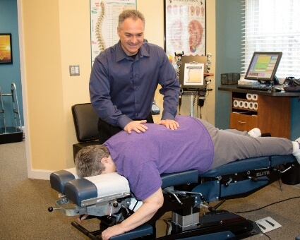 Palmyra chiropractor Dr. Carmelo Caratozzolo adjusting a patient 