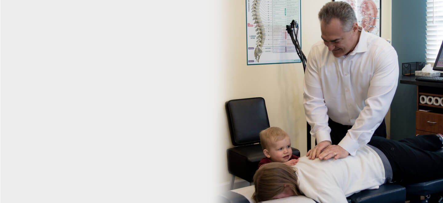 Palmyra chiropractor adjusting patient while her son watches