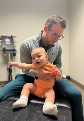 Dr. John holding baby while doing adjustment