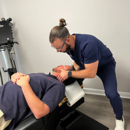 Adjusting man's neck on table