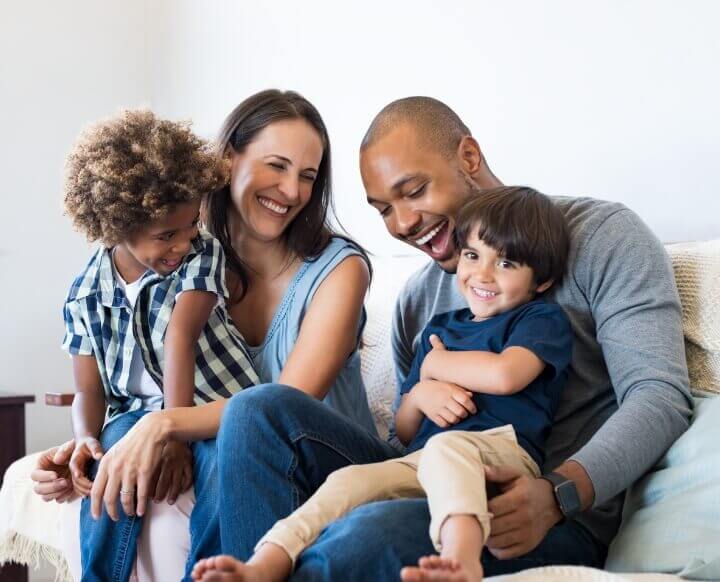 happy family of four sitting on couch