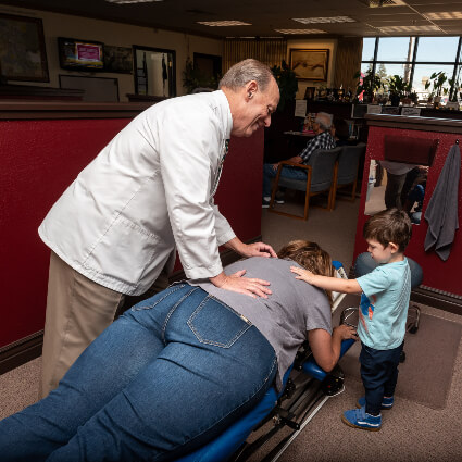 Chiropractor and child touching woman's back