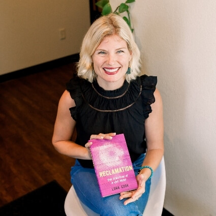 Dr. Lona sitting with her book