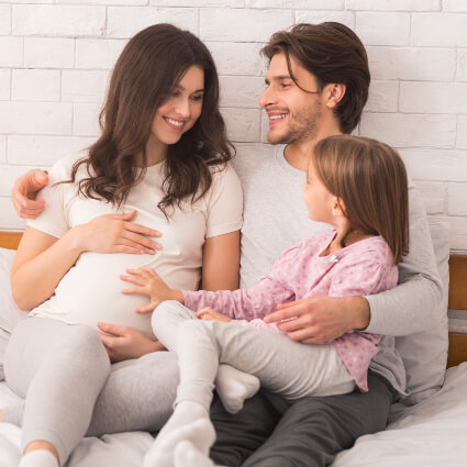 Pregnant mom with family on bed