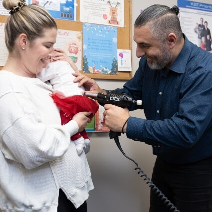 Restore Chiropractic & Wellness Centre patient holding a baby who is being adjusted