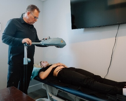 Old Town health coach Colin La Grange assisting patient with laser therapy