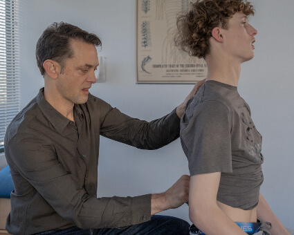 Dr. Chad checking young man's spine