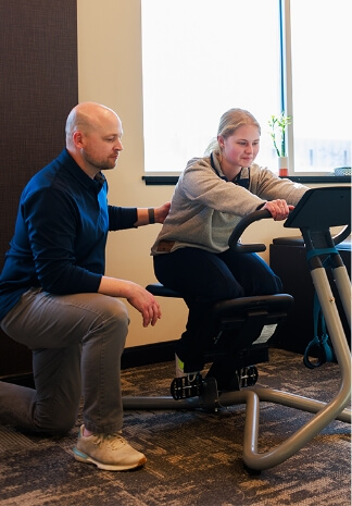 New Hope chiropractor Dr matthew helping patient on workout bike