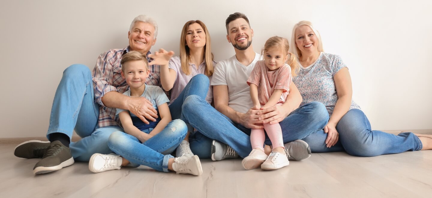 multigenerational family sitting together on a wood floor