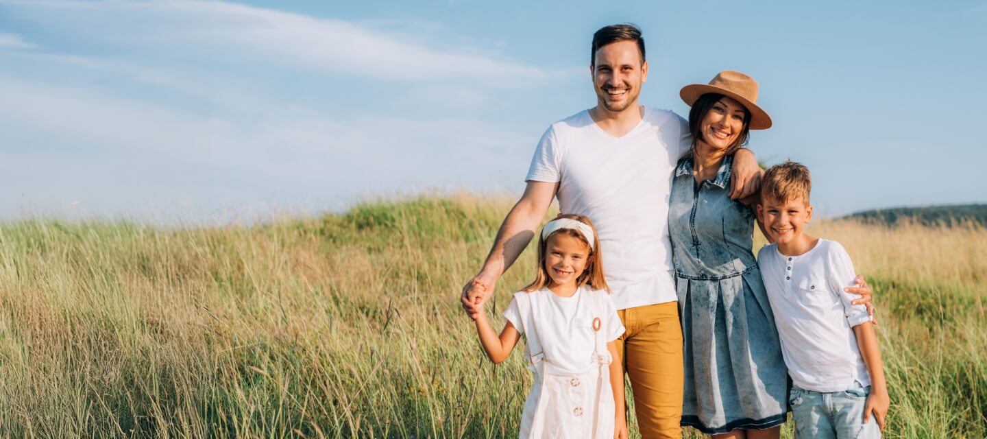 smiling family of four in a lush green field