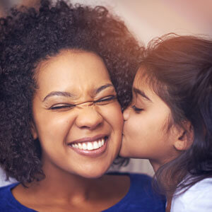 little girl kissing mom on the cheek