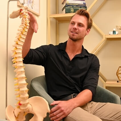 Wilmington chiropractor pointing at spine model