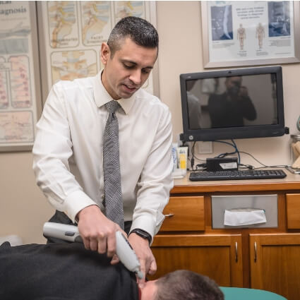 McMurray & Ellahie Chiropractic chiropractor adjusting patients neck with tool