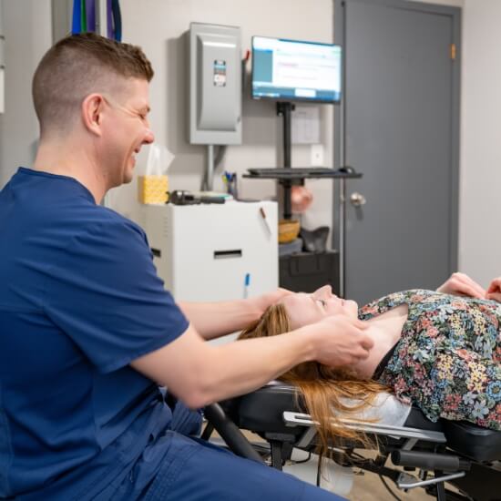 Sioux City Chiropractor Dr. Davis smiling while adjusting patient