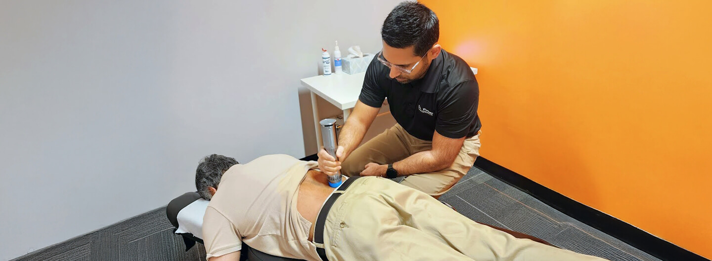 Dr. Pranav using a chiropractic tool to adjust a Flowery Branch patient