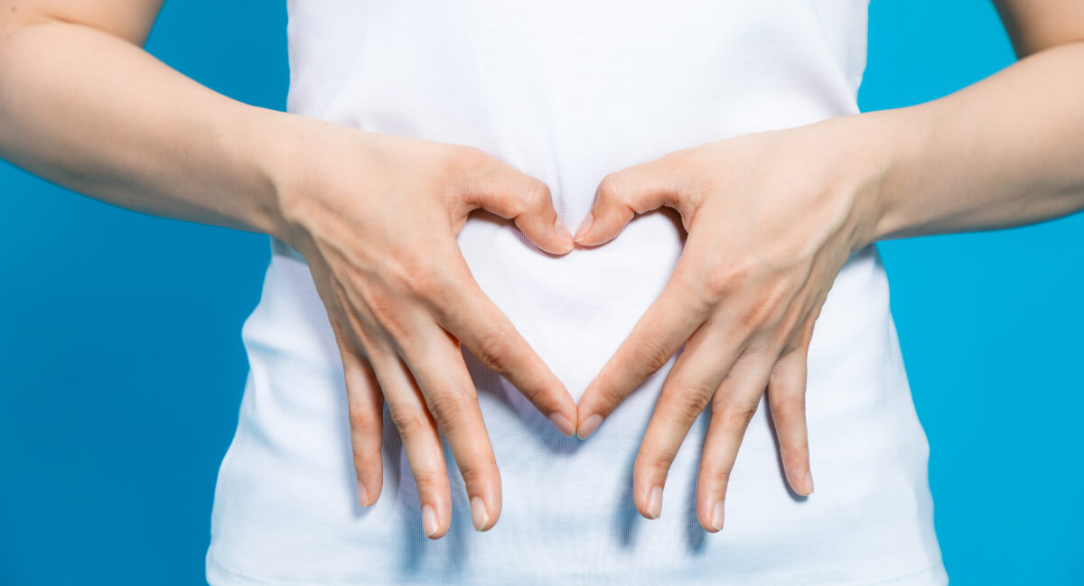 Heart shape with fingers on stomach