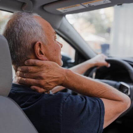 man in car holding neck in pain