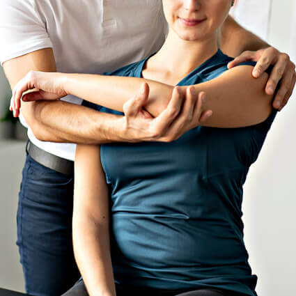 woman in blue shirt doing arm stretch with therapist