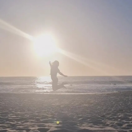 happy person on beach jumping in the air