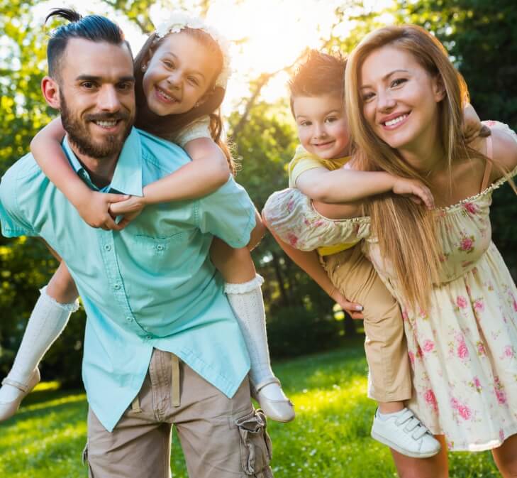 family of four smiling outdoors