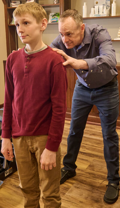 Chiropractor inspecting pediatric patient's back