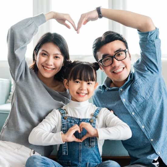 family of 3 making heart shape with their arms