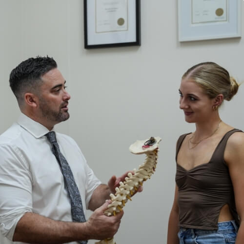 Dr William discussing a spine model with a Upper Mount Gravatt patient
