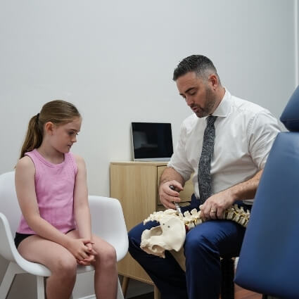 Chiropractor discussing spine with pediatric patient
