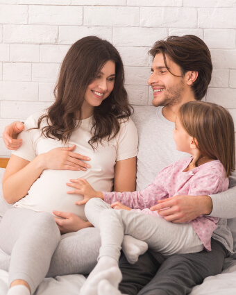 Family of three sitting on bed