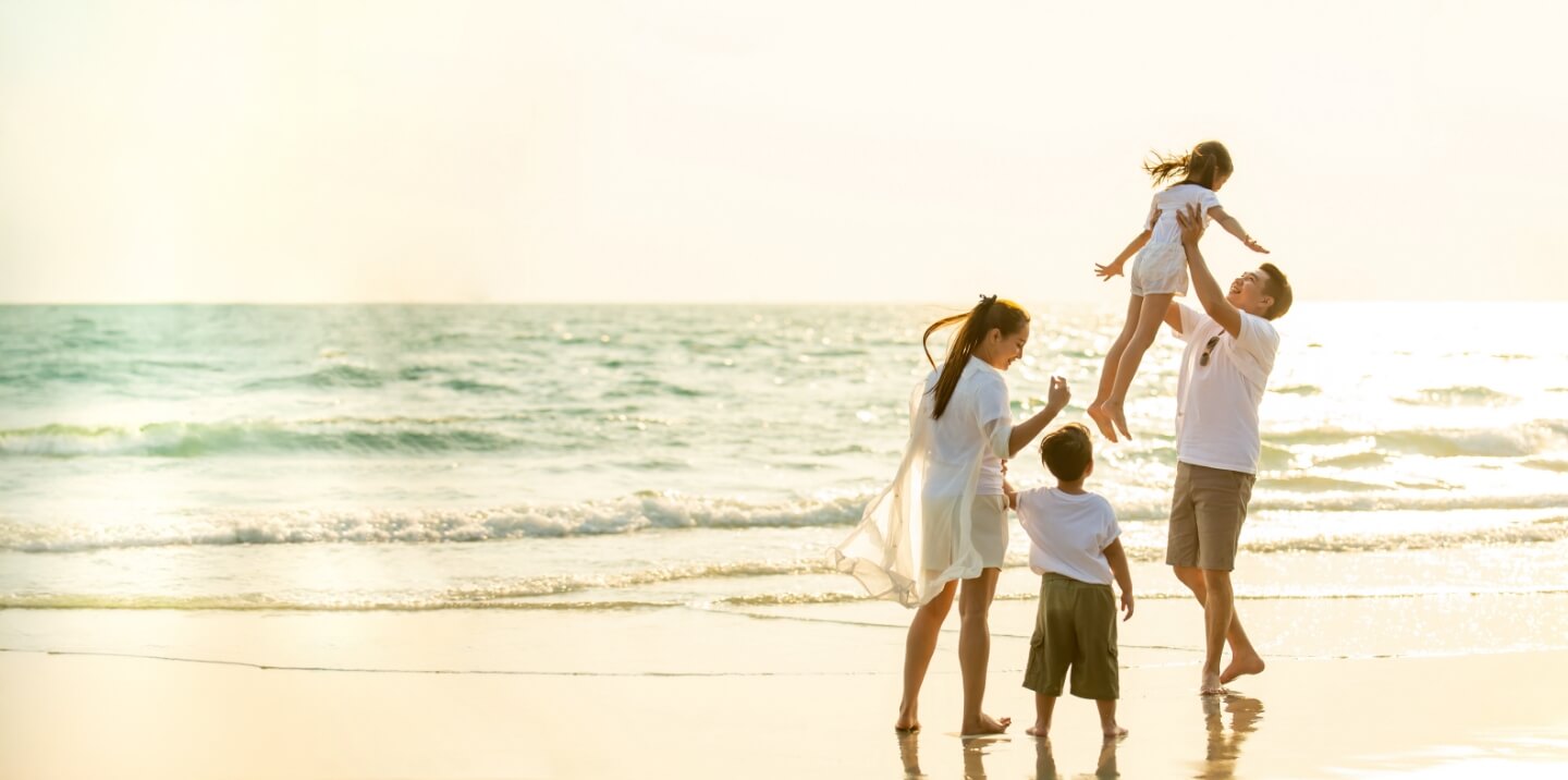 family of 4 walking on beach at sunset