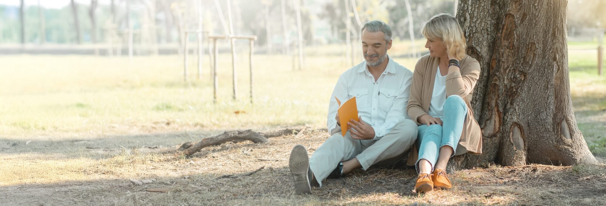 man and woman sitting near tree in a park