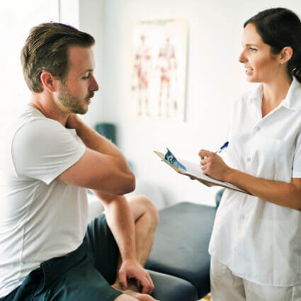 Man on adjustment table talking with chiropractor about shoulder
