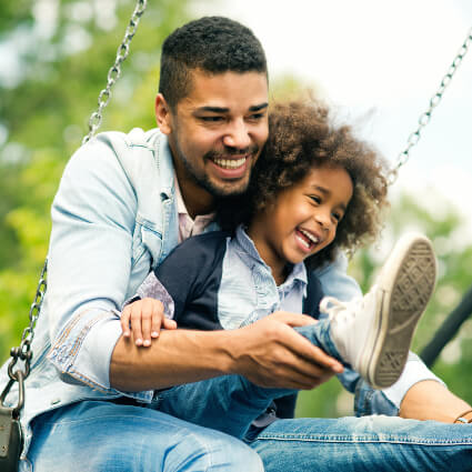 Dad and daughter playing on a swing